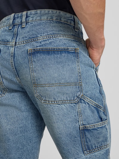 Männermodel trägt Shorts mit Kontrastnähten Modell 'Mito' von Redefined Rebel aus reiner Baumwolle mit Eingrifftaschen, Ganzkörperansicht Rückansicht.