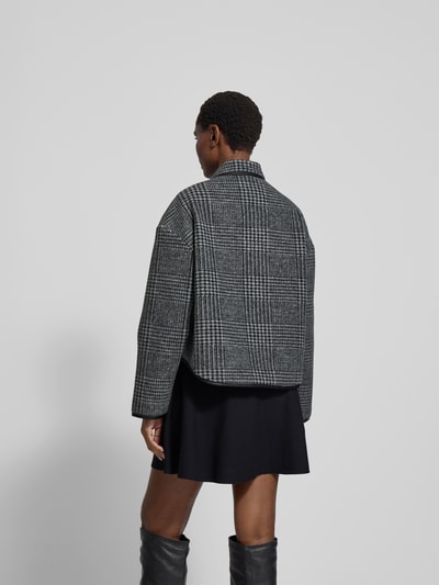 Frauenmodel trägt Jacke mit Knopfleiste von Anine Bing z mieszanki materiałów z dodatkiem wełny, luźny krój, kołnierzyk koszulowy, wpuszczane kieszenie, długość tyłu 60 cm, szerokość klatki piersiowej 57 cm, długość rękawów 53 cm, kratka szaro-czarna, tekstura miękka, całkowity widok od tyłu.