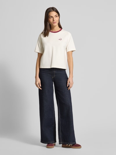 Frauenmodel trägt Regular Fit T-Shirt mit Strasssteinbesatz von Marc Cain in Creme mit Rundhalsausschnitt und elastischer Baumwoll-Mix mit Modal-Anteil, Ganzkörperansicht von vorne.