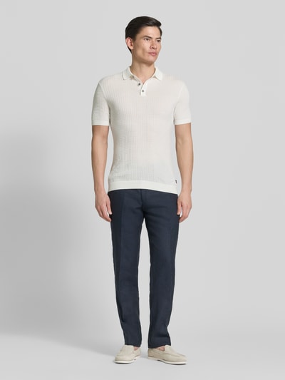 Männermodel trägt Slim Fit Poloshirt in Strick-Optik Modell 'Vanceo' von JOOP! Collection aus reiner Baumwolle, Ganzkörperansicht von vorne.