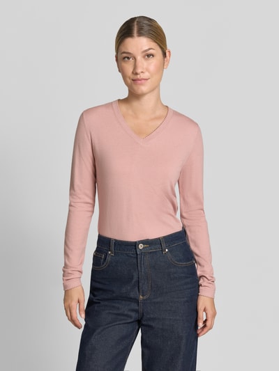 Frauenmodel trägt Pullover aus Viskose-Mix mit V-Ausschnitt von Christian Berg Woman in Rosa, gerader Schnitt, gerippte Abschlüsse, Jeans, Ganzkörperansicht von vorne.