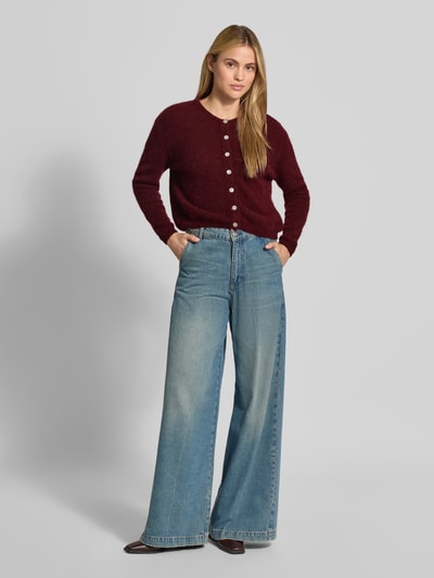 Kobiece modelka nosi kardigan Relaxed Fit Cardigan aus Woll-Alpaka-Mix Model 'VITOW' od American Vintage, kolor bordowy, imitacja dzianiny, z mieszanki wełny i alpaki, listwa guzikowa, okrągły dekolt, długość tyłu w rozmiarze S 52 cm, długość rękawów w rozmiarze S 56 cm, pełny widok z przodu.