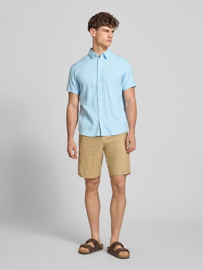 Männermodel trägt Slim Fit Leinenhemd mit Viskose-Anteil Modell 'Bobby' von Blend in Hellblau, Kentkragen, Kurzarm, Ganzkörperansicht von vorne.