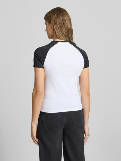 Vrouwenmodel draagt Slim Fit T-shirt met ronde hals en logo van Guess Jeans in zwart-wit, mix van katoen en elastaan, ruglengte maat S 53 cm, slim fit. Ganzkörperansicht Rückansicht.