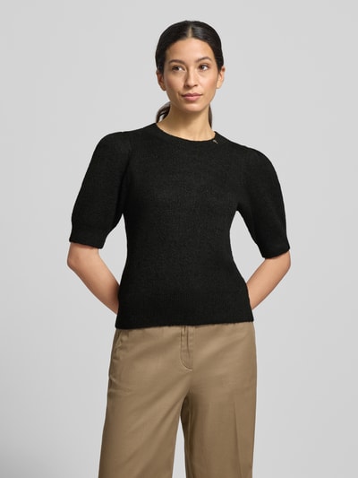 Modelka nosi Strickpullover mit gerippten Abschlüssen Modell 'Kylie' od JOOP!, czarny, luźny krój, materiał z domieszką wełny, półdługie rękawy, detale marki, okrągły dekolt, tekstura dzianiny, widok całej sylwetki z przodu