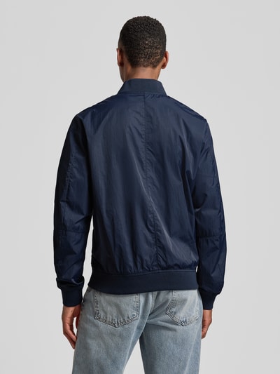 Männermodel trägt Regular Fit Bomberjacke mit Stehkragen von s.Oliver RED LABEL in Dunkelblau, unifarben, Ganzkörperansicht Rückansicht.