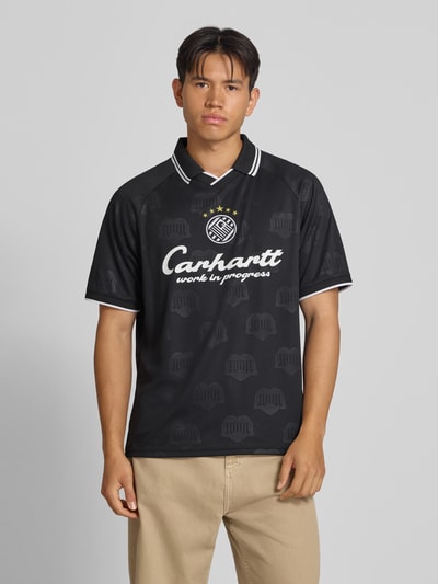 Männermodel trägt Funktionsshirt mit Logo Modell 'Terrace' von Adidas, Schwarz mit weißem Logo, Regular Fit, Rundhalsausschnitt, Ganzkörperansicht von vorne, Herren Funktionsshirt, Rückenlänge bei Größe M: 71 cm.