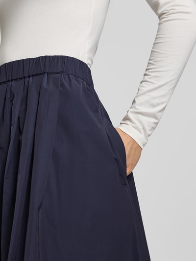 Vrouwenmodel draagt Midirock met elastische tailleband van Christian Berg Woman Selection, donkerblauw met plooien, detailopname taille.