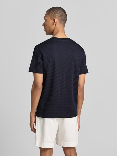 Männermodel trägt T-Shirt mit Strukturmuster Modell 'Raulos' von JOOP! Collection aus reiner Baumwolle, Modern Fit, Rückenansicht.