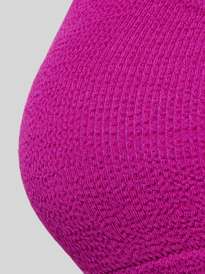Frauenmodel trägt Bikini-Oberteil mit Label-Detail Modell 'JUSTIN' von Banana Moon in kräftigem Pink, Struktur-Textur, Material-Mix mit Stretch-Anteil, Körpernaher-Schnitt, Modell 'JUSTIN', Label-Detail, Nahaufnahme Oberkörper.