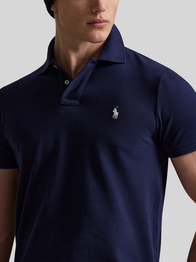 Männermodel trägt Regular Fit Poloshirt aus reiner Baumwolle von Polo Ralph Lauren, unifarben, Logo-Detail, Nahaufnahme Oberkörper.