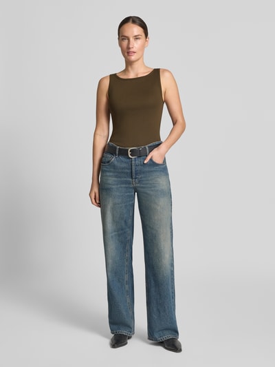 Frauenmodel trägt Regular Fit Tanktop aus reiner Baumwolle von Marc O'Polo in Oliv, kombiniert mit blauer Jeans, Ganzkörperansicht von vorne.