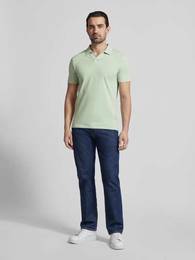 Männermodel trägt Slim Fit Poloshirt mit V-Ausschnitt von Lindbergh in zartem Grün, Baumwoll-Elasthan-Mix, Ganzkörperansicht von vorne.