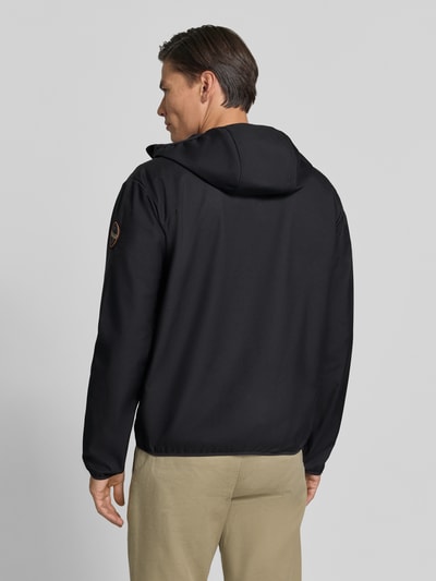 Männermodel trägt schwarze Regular Fit Jacke mit Logo-Print von Napapijri, glatte Textur, elastische Abschlüsse, Ganzkörperansicht Rückansicht. Kontext: Herren Jacke von Napapijri, Stehkragen, Eingrifftaschen mit Reißverschluss, Reißverschluss, Rückenlänge bei Größe M 69 cm, Schulterbreite 52 cm, Brustweite 60 cm, Ärmellänge 68 cm.