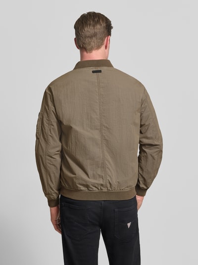 Männermodel trägt Blouson mit Label-Patches Modell 'IBE' von khujo in Oliv, strukturierte Oberfläche, Gerader-Schnitt, Rückenansicht.