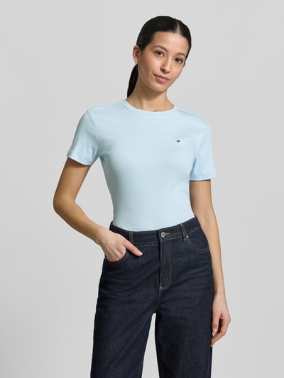 Frauenmodel trägt Slim Fit T-Shirt aus reiner Baumwolle von Tommy Hilfiger, Optik: Unifarben, Passform: Slim Fit, Logo-Stitching, Rundhals, Kurzarm, Jersey, Material: reine Baumwolle, Hellblau, glatte Textur, Ganzkörperansicht von vorne.