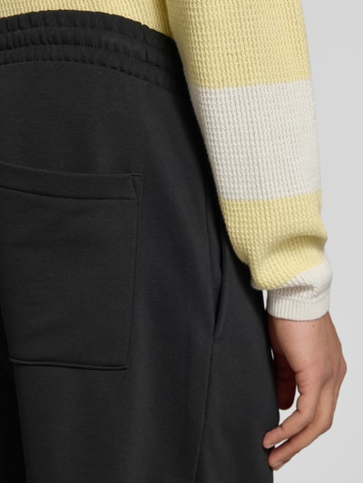 Männermodel trägt Regular Fit Shorts mit Label-Stitching von REVIEW aus Baumwoll-Mix, schwarz, Detailaufnahme Gesäßtasche.