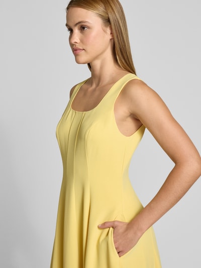Frauenmodel trägt Midikleid mit Rundhalsausschnitt Modell 'ARLOTT' von Ted Baker, A-Linie, breite Träger, Rückenreißverschluss, Nahaufnahme Oberkörper. Rückenlänge bei Größe 36: 107 cm, Brustweite bei Größe 36: 44 cm, gelbe Farbe, feine Struktur.