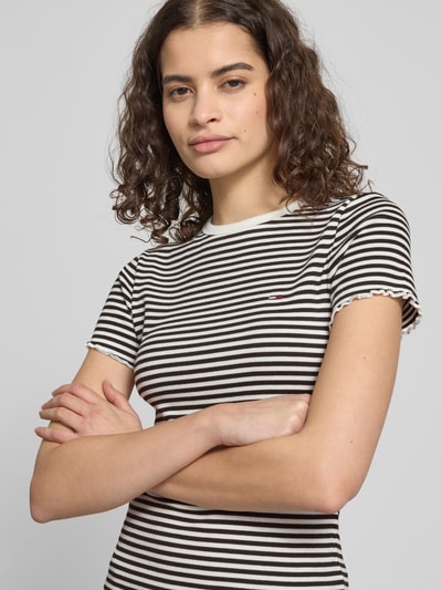 Frauenmodel trägt Slim Fit T-Shirt aus Baumwoll-Mix von Tommy Hilfiger mit schwarz-weißen Streifen, Logo-Detail, Feinrippstruktur, Rundhals, Frill an Ärmeln und Saum, Nahaufnahme Oberkörper.