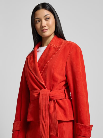 Frauenmodel trägt Lederjacke mit Bindegürtel von Marc Cain aus Echtem Leder, taillierter Schnitt, Reverskragen, leuchtendes Rot, Nahaufnahme Oberkörper.
