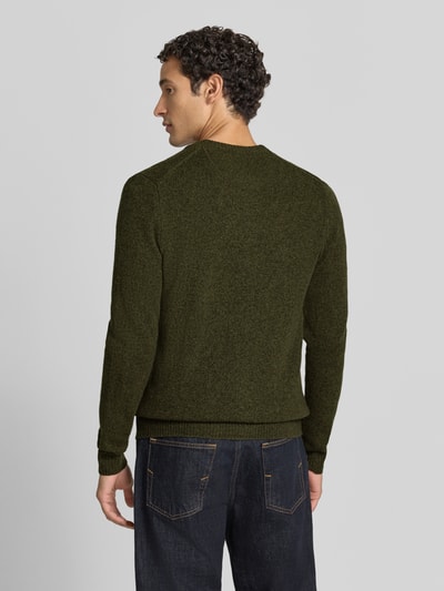 Männermodel trägt Regular Fit Strickjacke aus reiner Wolle mit Logo-Stickerei von MCNEAL in Dunkelgrün, gerippte Abschlüsse, Ganzkörperansicht Rückansicht. Rückenlänge bei Größe M 69 cm, Ärmellänge 74 cm, gerippter Kragen, langärmliges Design, durchgängiger Zipper.