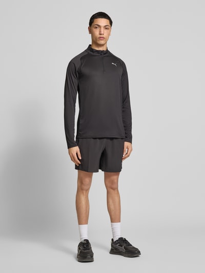 Männermodel trägt Langarmshirt mit Stehkragen und Reißverschluss von PUMA PERFORMANCE, Regular-Fit, Logo, schwarze Farbe, Ganzkörperansicht von vorne. Rückenlänge bei Größe M: 71 cm.