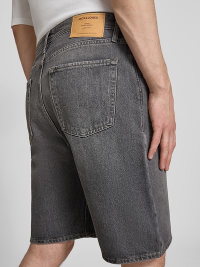 Männermodel trägt Baggy Fit Jeansshorts mit Eingrifftaschen Modell 'ALEX' von Jack & Jones aus reiner Baumwolle in Grau, Ganzkörperansicht Rückansicht.