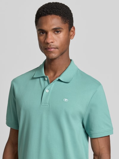 Männermodel trägt Regular Fit Poloshirt aus reiner Baumwolle von Tom Tailor in Mintgrün, glatte Struktur, Nahaufnahme Oberkörper.
