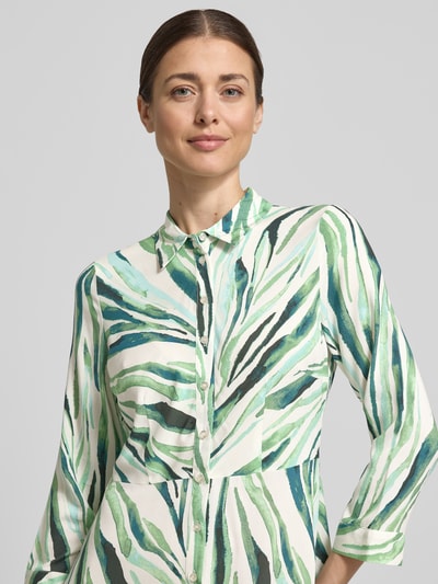 Frauenmodel trägt Hemdblusenkleid aus Reine Viskose Modell 'SAVANNA' von YAS, grün-weiß gemustert, Kentkragen, Knopfleiste, 3/4-Arm, Taillierte Passform, Midikleid, Nahaufnahme Oberkörper. Rückenlänge 135 cm, Brustweite 42 cm, Ärmellänge 49 cm, Größe S.