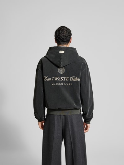 Männermodel trägt Oversized Jeansjacke aus Baumwoll-Mix von Don't Waste Culture, dunkel, elastische Abschlüsse, Ganzkörperansicht Rückansicht.