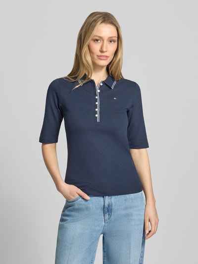 Frauenmodel trägt Slim Fit Poloshirt aus Lyocell-Mix von Tommy Hilfiger, Optik: Unifarben, Kontraststreifen, Logo-Stitching, Piqué, 1/2-Arm, Ganzkörperansicht von vorne.