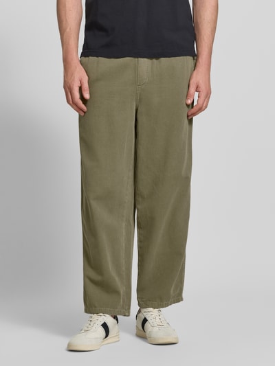 Männermodel trägt Jog Pants mit französischen Eingrifftaschen Modell 'LYCAZ' von American Vintage, olive, Baumwolle, Straight Fit, Nahaufnahme Oberkörper.