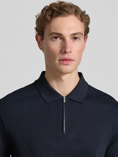 Männermodel trägt Slim Fit Poloshirt mit Reißverschluss Modell 'Franciscojose' von JOOP! Collection aus reiner Baumwolle, Nahaufnahme Oberkörper.