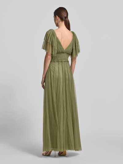 Frauenmodel trägt Maxikleid mit V-Ausschnitt und Taillenband von LACE & BEADS aus grünem Tüll, taillierter Schnitt, Ganzkörperansicht Rückansicht.