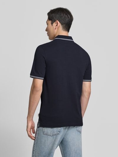 Männermodel trägt Regular Fit Poloshirt mit Logo-Stitching von bugatti in Dunkelblau, Reine Baumwolle, Ganzkörperansicht Rückansicht. Rückenlänge bei Größe M 71 cm, Polokragen, kurze Knopfleiste, Label-Detail.