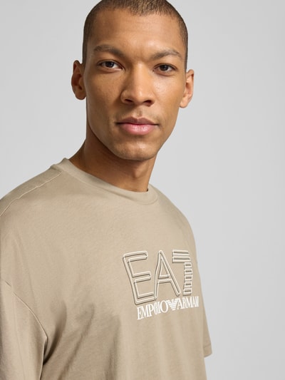 Männermodel trägt T-shirt mit Logo und ronde hals van EA7 Emporio Armani, puur katoen, regular fit, ruglengte maat M 68 cm, Nahaufnahme Oberkörper.