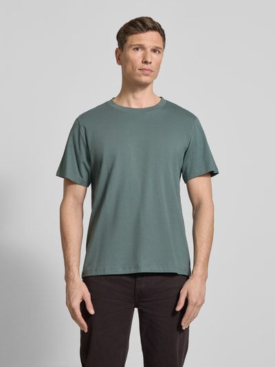 Męski model trägt Regular Fit T-Shirt aus reiner Baumwolle Modell 'ASPAN' von Selected Homme, efekt: jednolity kolor, okrągły dekolt, krótkie rękawy, dżersej, przód, krój regular fit, widok całej sylwetki z przodu.