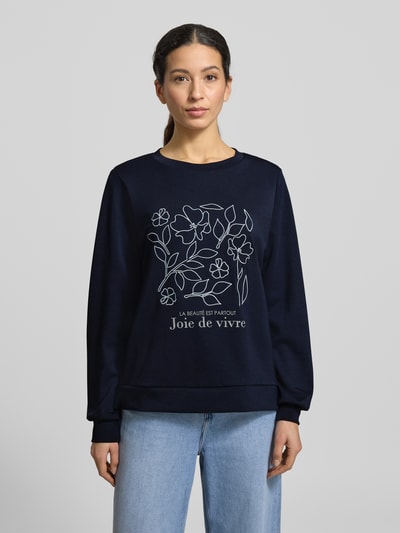 Frauenmodel trägt Sweatshirt mit Label-Print Modell 'BANU' von Soyaconcept in Dunkelblau, Rundhalsausschnitt, floraler Print, lockerer Schnitt, Modal-Mix, gerippte Abschlüsse, Ganzkörperansicht von vorne.