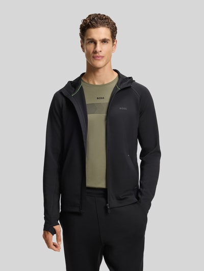 Männermodel trägt Regular Fit Trainingsjacke aus schnell trocknendem Gewebe Modell 'SICON ACTIVE' von BOSS Green in Schwarz, Ganzkörperansicht von vorne.