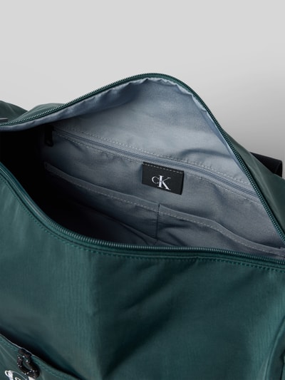 Produktfoto, Weekender met labelstitching van CK Calvin Klein in donkergroen, hoofvak met ritssluiting, binnenvak met rits, breedte 45 cm, lengte 24 cm, diepte 22 cm, schouderband 90 cm.