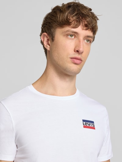 Männermodel trägt weißes slim fit T-shirt mit Levi's® Logo, glatte textuur, Slim Fit T-Shirt aus reiner Baumwolle im 2er-Pack Modell '2PK CREWNECK GRAPHIC' von Levi's®, heren T-shirt-set, Nahaufnahme Oberkörper.