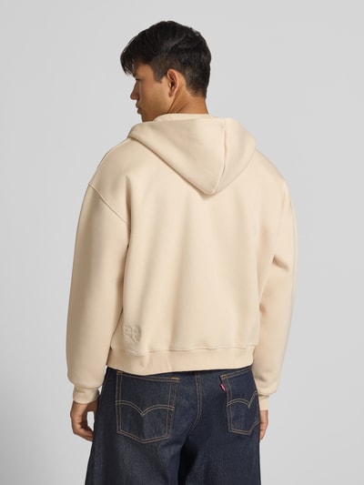 Männermodel trägt Sweatjacke mit Kapuze von ANOTHER COTTON LAB in Beige, lockerer Schnitt, glatte Struktur, Ganzkörperansicht Rückansicht.