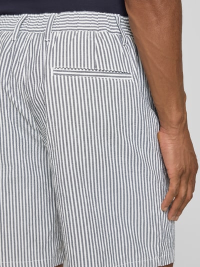 Mężczyzna nosi Regular Fit Bermudas aus Baumwoll-Mix Modell 'KARL' od SELECTED HOMME, pionowe paski, bawełniany seersucker, detal tylnej kieszeni, krój regular fit, zbliżenie na biodro z tyłu.