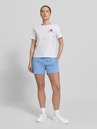 Frauenmodel trägt T-Shirt mit Rundhalsausschnitt und Label-Stitching von Gant aus Reine Baumwolle, Regular-Fit, Rückenlänge 57 cm, Ganzkörperansicht von vorne.