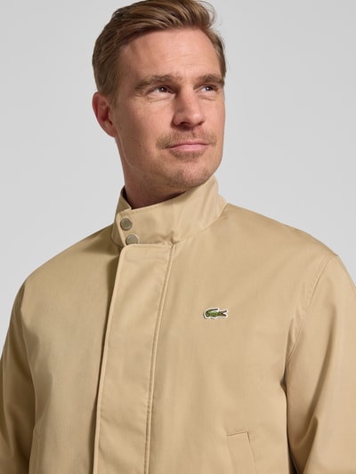 Męski model nosi Regular Fit Bomberka z bawełną Model 'HARRINGTON' od Lacoste, jednokolorowa, wyhaftowane logo, stójka, listwa guzikowa, wpuszczane kieszenie, zapięcie na zamek, prążkowane zakończenia; zbliżenie na górną część ciała.