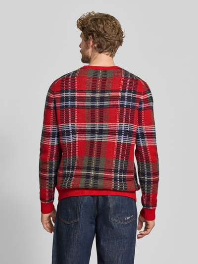 Männermodel trägt Oversized Pullover aus reinem Kaschmir von Christian Berg Men in Rot mit Karo-Muster, elastische Abschlüsse, Ganzkörperansicht Rückansicht.