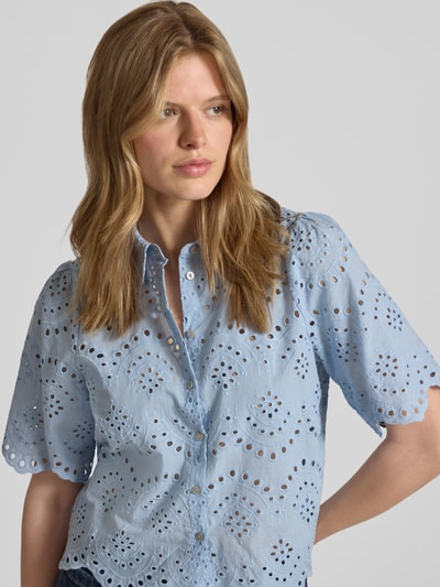 Vrouwenmodel draagt Loose Fit Blouse met opengewerkte details model 'VALAIS' van Only, lichtblauw katoen, effen look, hemdkraag, lange mouw, knoopsluiting, manchetten, borst en schouder in detail getoond, close-up bovenlichaam.