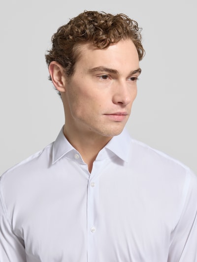 Männermodel trägt weißes Business-Hemd mit Kentkragen Modell 'KENNO' von HUGO, Baumwoll-Elasthan-Mix, Slim Fit, Nahaufnahme Oberkörper.