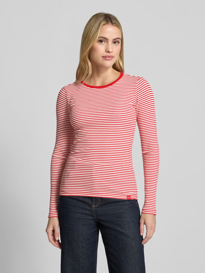 Frauenmodel trägt Longsleeve in Ripp-Optik mit Rundhalsausschnitt von Smith and Soul, Slim Fit, rot-weiß geringelt, Baumwoll-Elasthan-Mix, Allover-Look, Ganzkörperansicht von vorne.