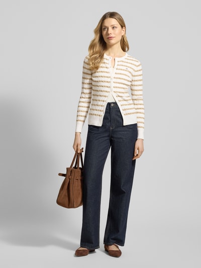Frauenmodel trägt Strickjacke mit Baumwoll-Anteil von Gant, körpernaher Schnitt, Zopfmuster, Knopfleiste, Jeans, Ganzkörperansicht von vorne.